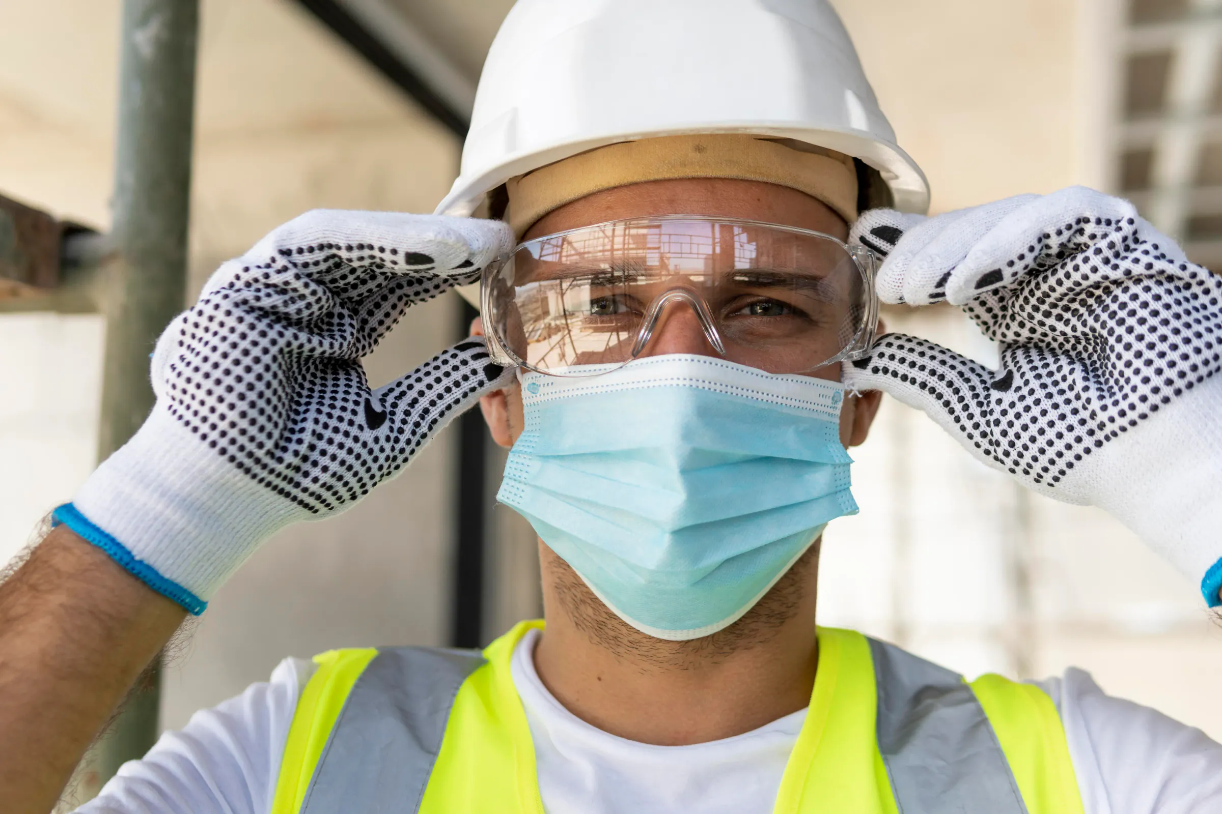 Worker wearing safety glasses and PPE on a construction site.