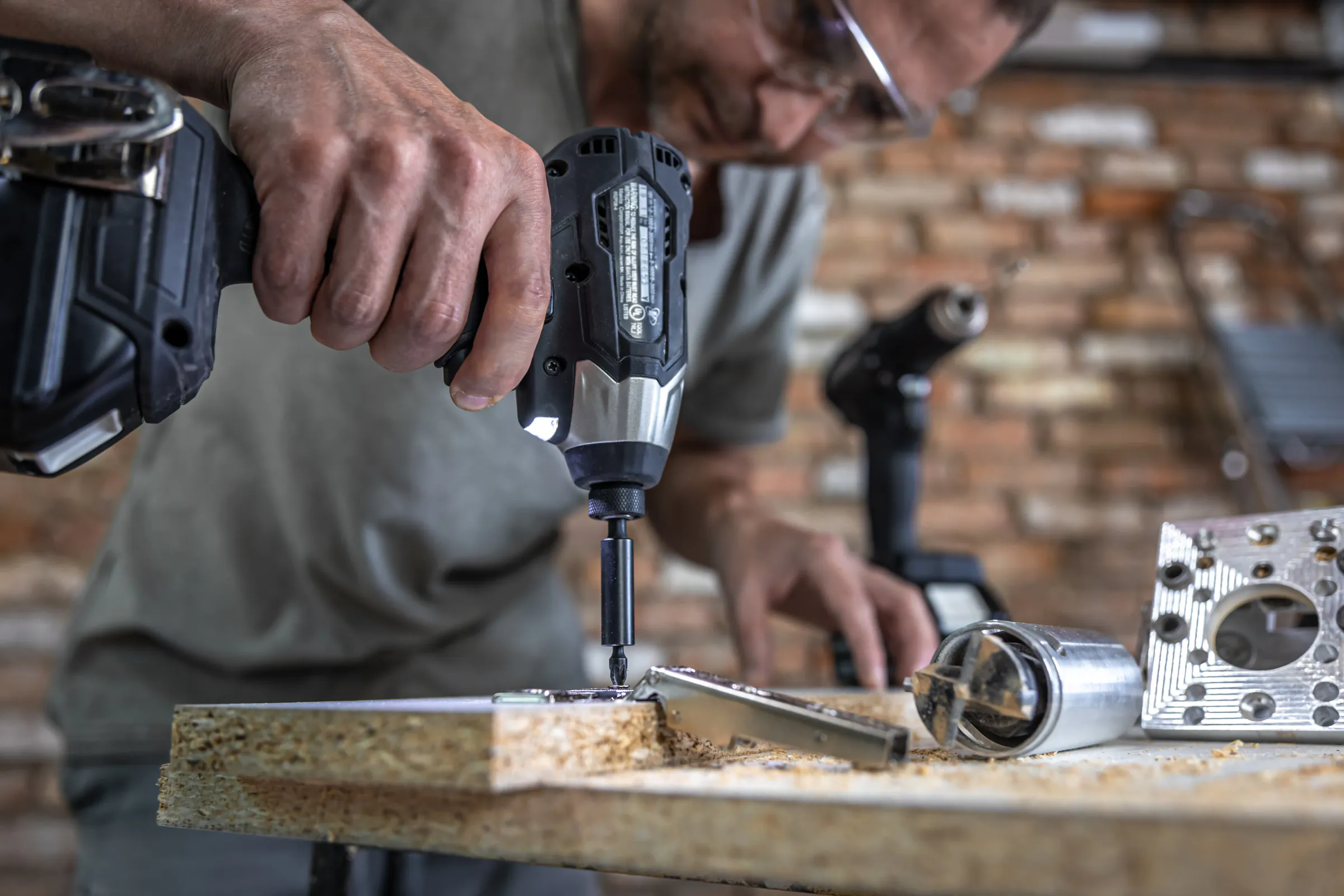 Self-tapping screw being driven into metal using power tools, representing fastening and tools.